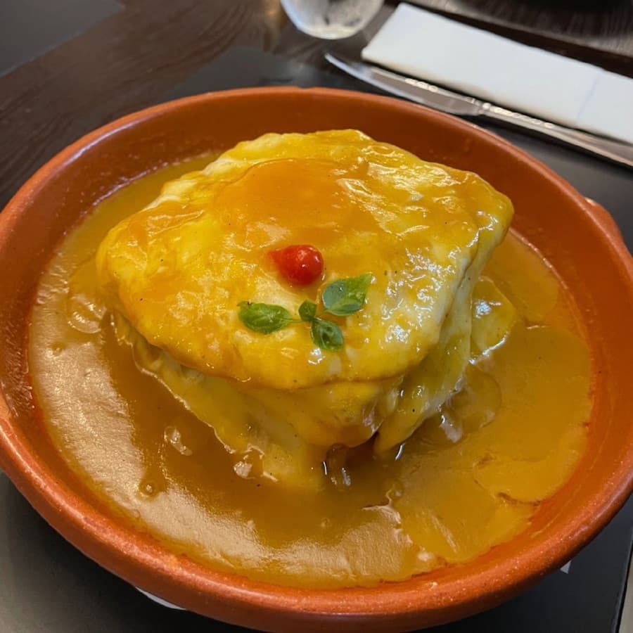 Francesinha at Restaurante O Vareiro, covered in melted cheese and rich sauce